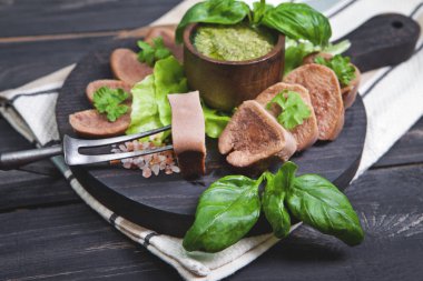 Pesto ve salata ile koyu ahşap tabloda haşlanmış Dana dil