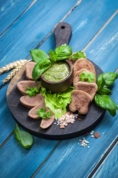 Pesto ve salata ile koyu ahşap tabloda haşlanmış Dana dil