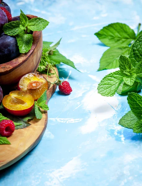 Pflaumen Und Himbeeren Mit Grünen Blättern Holzschale Auf Blauer Oberfläche — Stockfoto