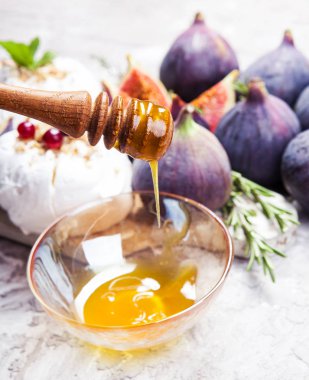 Mini pavlova pastalar, incir, kızılcık, otlar ve ön plan üzerinde bal