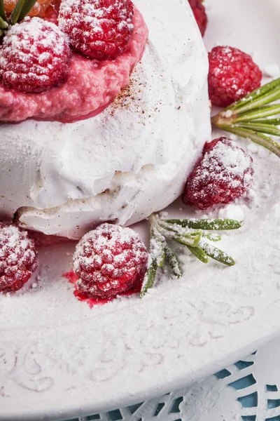 Meringue pavlova cake served with whipped cream and fresh raspberries