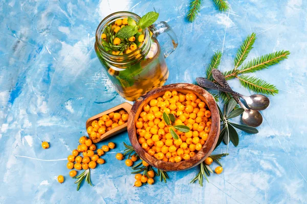 Deniz topalak çay kavanozuna çilek ve mavi arka plan üzerinde ahşap kase çilek