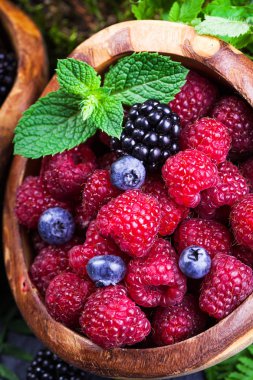 Yeşil yaprakları ile ahşap kase taze çeşitli meyveler