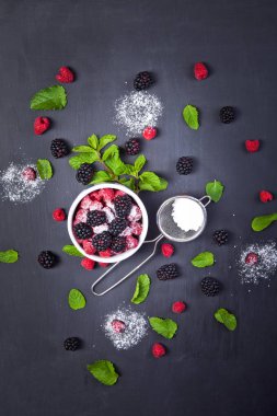 Çeşitli taze çilek nane ile bırakır. Ahududu ve böğürtlen koyu arka planda. Sağlıklı organik gıda.