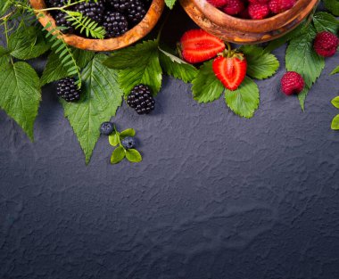 Tahta kasede taze meyveler. Sulu ve taze yabanmersinli böğürtlen 6 böğürtlen ve ahududu kırsal alanda yeşil yapraklı. Sağlıklı yeme ve beslenme konsepti