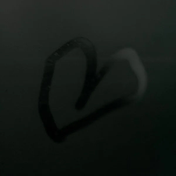 A heart in the window of a foggy car