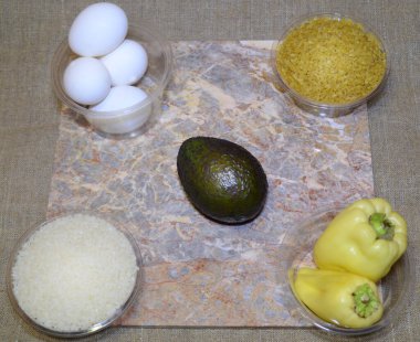 Lezzetli bulgur pişirmek için gereken malzemeler: pirinç, yumurta, dolma biber ve avokado.