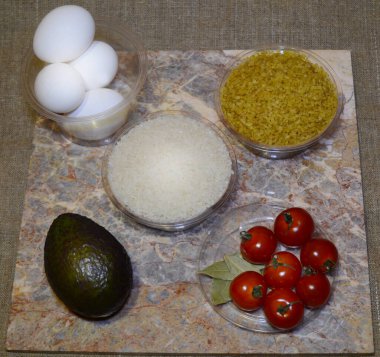 Lezzetli doğu yemekleri için malzemeler: yumurta, bulgur, pirinç, avokado, kiraz domatesleri, defne yaprağı