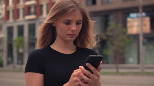 Mooi duizendjarige meisje gebruik mobiele in stad — Stockvideo