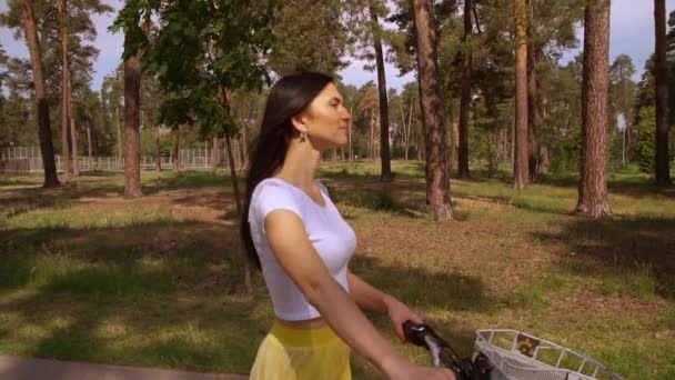 大人の白人女性は 彼女の自転車を運ぶ公園で歩きます 自然の景色を楽しみながら周り黄色のスカートを身に着けている美しい女性に見える — ストック動画