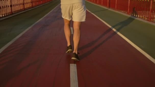 Jeune homme séduisant court sur le pont le long de la rivière — Video