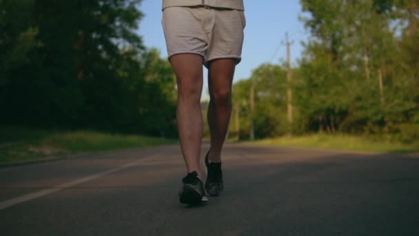 Närbild av en löpare fötter kör på en väg. — Stockvideo