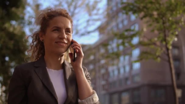 Mujer encantadora pelo rizado tiene una conversación positiva en el teléfono — Vídeo de stock