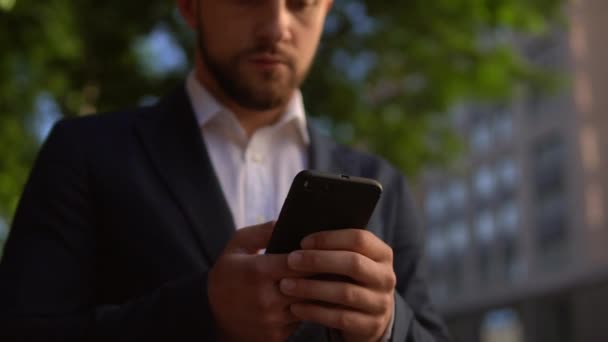 Vousatý muž v modrém obleku drží smartphone — Stock video