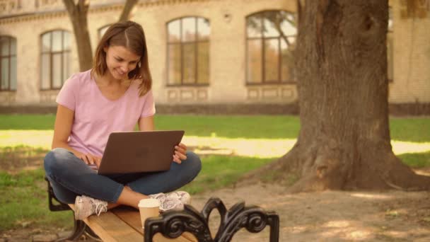 Молодая женщина пользуется компьютером возле колледжа — стоковое видео