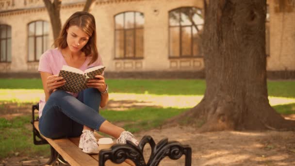 Mujer joven estudiando cerca de la universidad — Vídeos de Stock