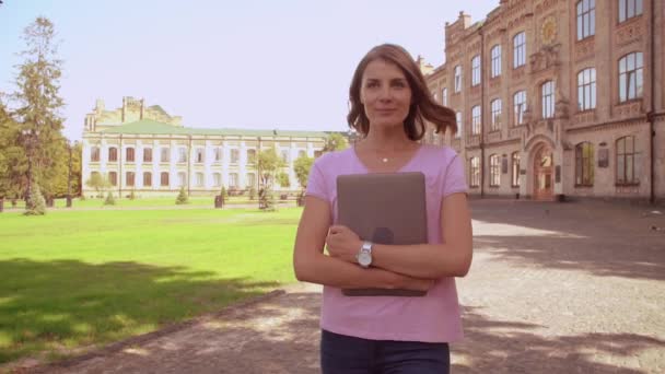 Vrouw met laptop loopt op het gebied van de campus — Stockvideo