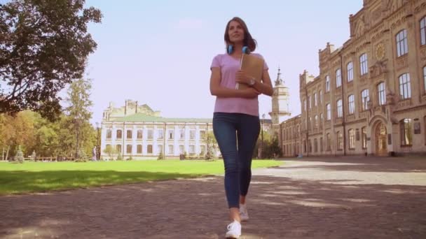Šťastná žena držící knihy procházky v areálu kampusu — Stock video