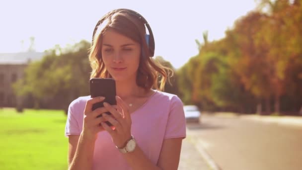 Portret student luisteren muziek texting buitenshuis — Stockvideo