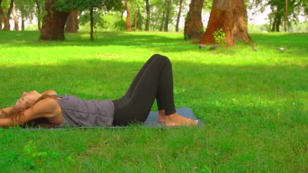 Štíhlá žena cvičení asana v parku — Stock video