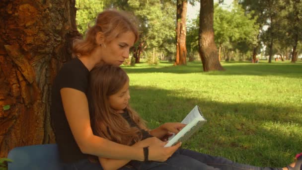 Дочь читает книгу со своей матерью — стоковое видео