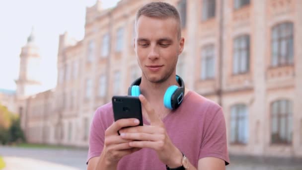 Homme avec écouteurs textos message à l'extérieur — Video