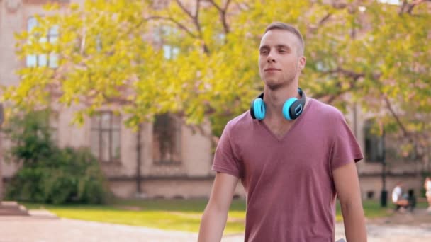 Étudiant marchant dans la zone du campus tenant livre — Video