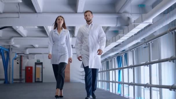 Personas que llevan uniforme caminando en el laboratorio — Vídeo de stock
