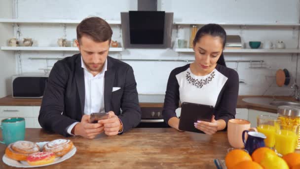 Man en vrouw zitten in hun keuken in de ochtend — Stockvideo