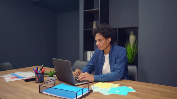 Mixed-race jonge man werken op zijn laptop — Stockvideo
