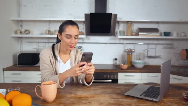 Dona de casa verifica rede social enquanto sentado na cozinha — Vídeo de Stock