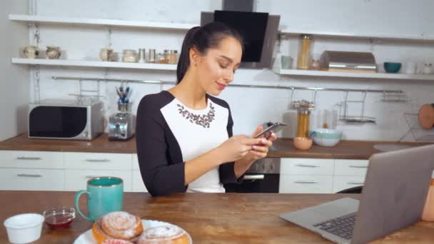 Mooie mooie dame bedrijf smartphone op keuken — Stockvideo