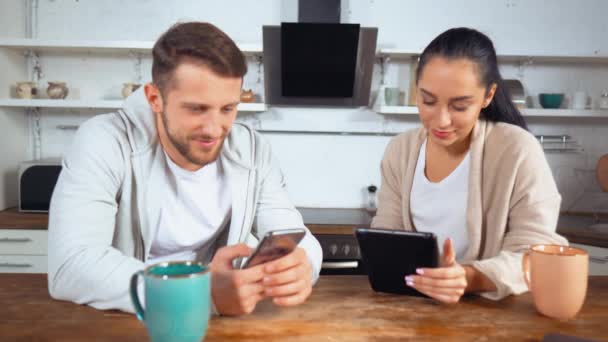 Joven pareja de negocios pasa la mañana en la cocina casera — Vídeos de Stock