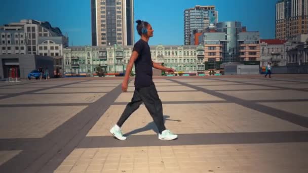 Estudante feliz com fones de ouvido andar na cidade moderna — Vídeo de Stock