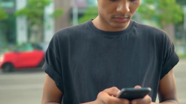 Человек, стоящий на улице и печатающий на смартфоне — стоковое видео