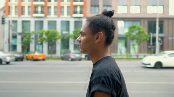 Vista lateral joven hipster hombre caminando en la calle — Vídeos de Stock