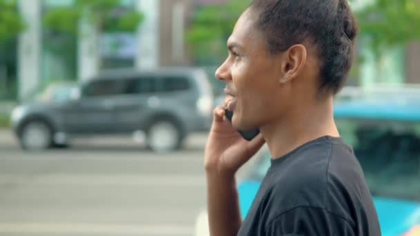 Zijaanzicht jonge hipster man chat door smartphone wandelen op straat — Stockvideo
