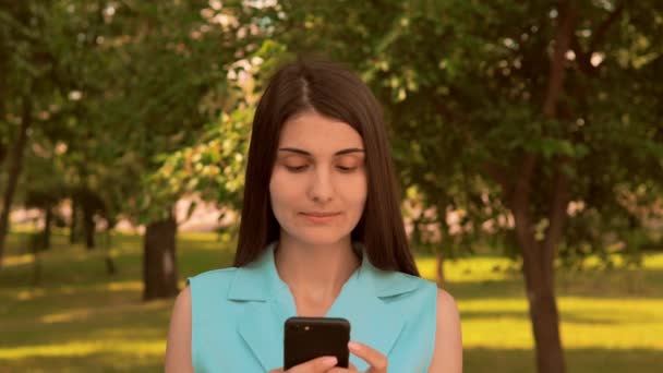 Retrato sorrindo mulher caucasiana usando móvel no parque — Vídeo de Stock