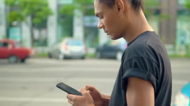 Profilja afro-amerikai ember séta gazdaság okostelefon az utca mentén, a város — Stock videók