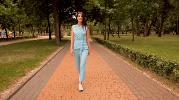 Νέα καυκάσιος γυναίκα περπατάει στο δρόμο στο πάρκο της πόλης — Αρχείο Βίντεο