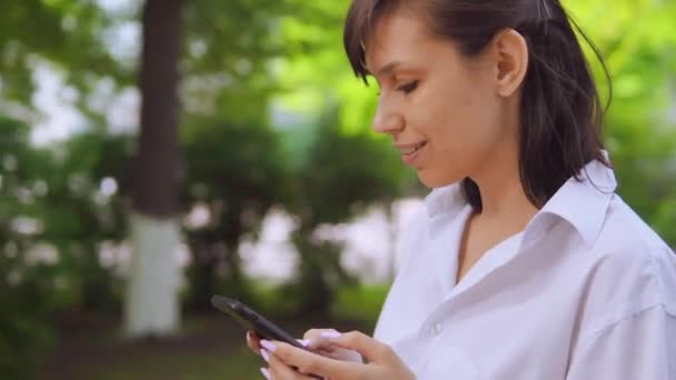 Lado vista millennials menina bate-papo on-line em fuga no parque — Vídeo de Stock