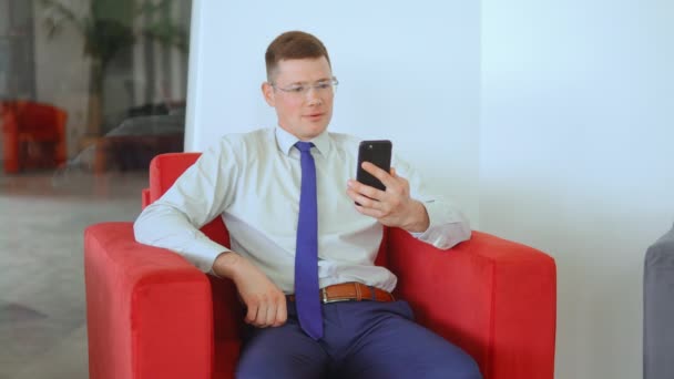 Mladý podnikatel používající smartphone pro online volání v interiérech — Stock video