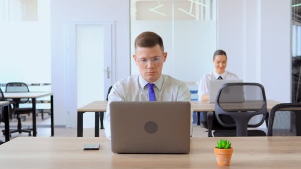 Retrato hombre de negocios sobrecargado de trabajo utilizando portátil en el lugar de trabajo — Vídeos de Stock