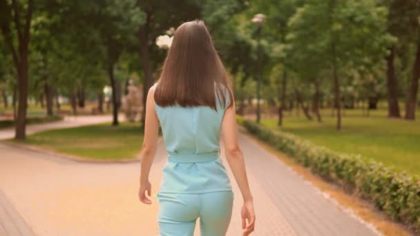 Tillbaka visa närbild kvinna promenader på gatan i stadsparken sommar utomhus — Stockvideo