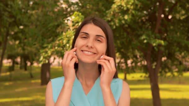 Портрет веселая молодая женщина использовать наушники на открытом воздухе — стоковое видео