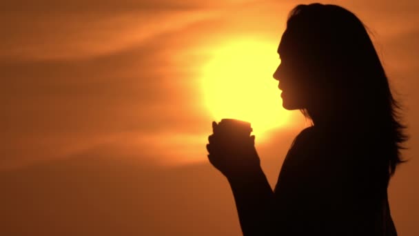 Vrouw holding cup met om te gaan drinken zon opkomen in de hemel — Stockvideo