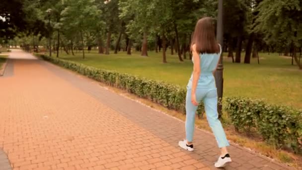 Вид сзади женщина, идущая по улице в городском парке летние наружные — стоковое видео