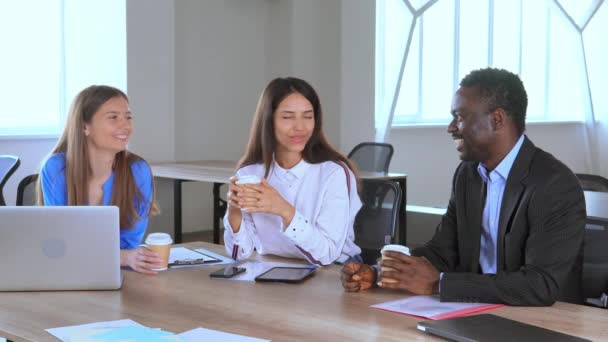 Diverse Mitarbeiter sitzen am Arbeitsplatz und unterhalten sich beim Mittagessen lachend — Stockvideo