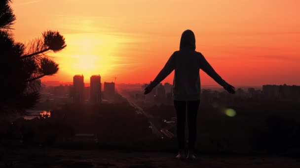 Mulher silhueta ao nascer do sol mãos nascentes vista urbana da cidade — Vídeo de Stock