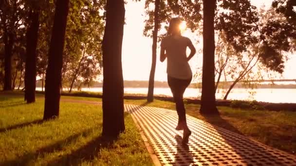 Alegre mujer corriendo en parque saltar en la orilla del río — Vídeos de Stock